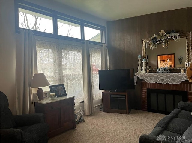 carpeted living room with a fireplace and wooden walls