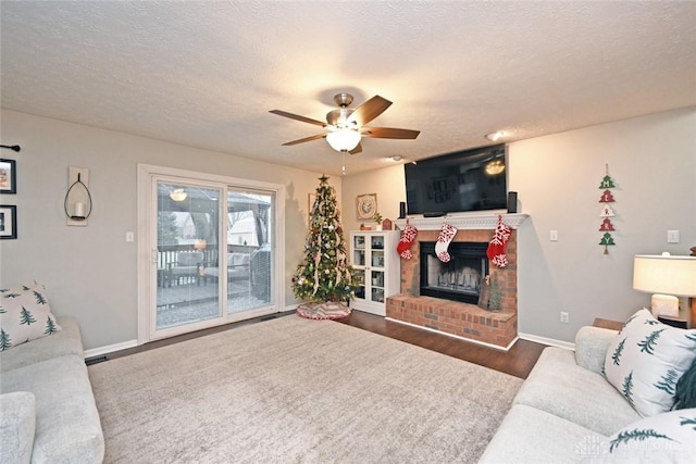 living room with dark hardwood / wood-style flooring, ceiling fan, a fireplace, and a textured ceiling