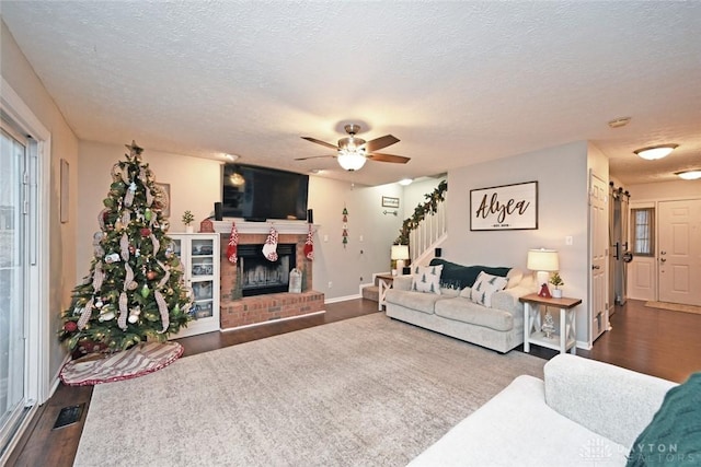 living room featuring a fireplace, a textured ceiling, dark hardwood / wood-style flooring, and ceiling fan