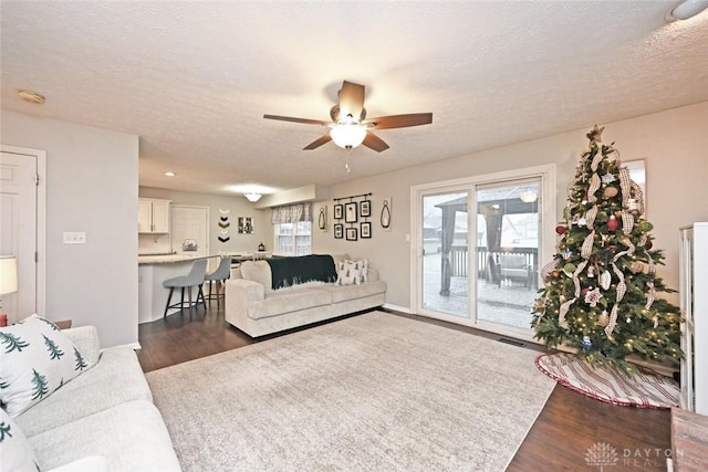 living room with dark hardwood / wood-style flooring, a textured ceiling, and ceiling fan