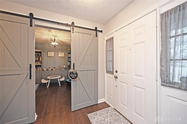 entryway with dark hardwood / wood-style flooring, a barn door, and a textured ceiling