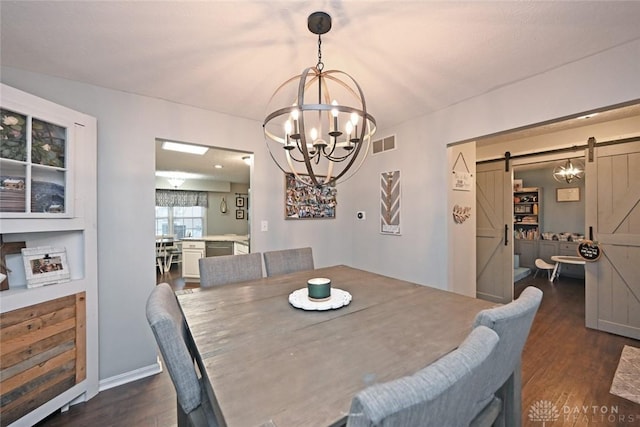 dining space with a barn door, dark hardwood / wood-style floors, and an inviting chandelier