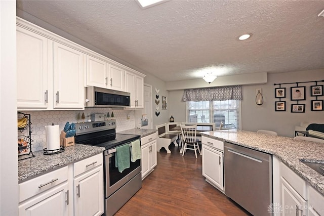 kitchen with white cabinets, decorative backsplash, stainless steel appliances, and a textured ceiling