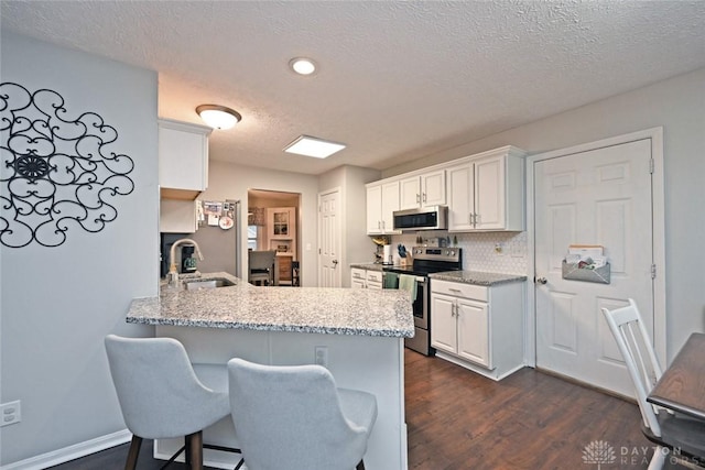 kitchen featuring kitchen peninsula, appliances with stainless steel finishes, white cabinetry, and sink