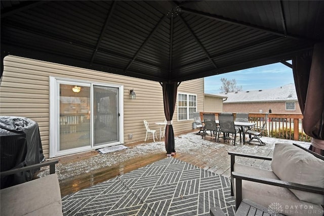 snow covered patio with a gazebo, grilling area, and a wooden deck