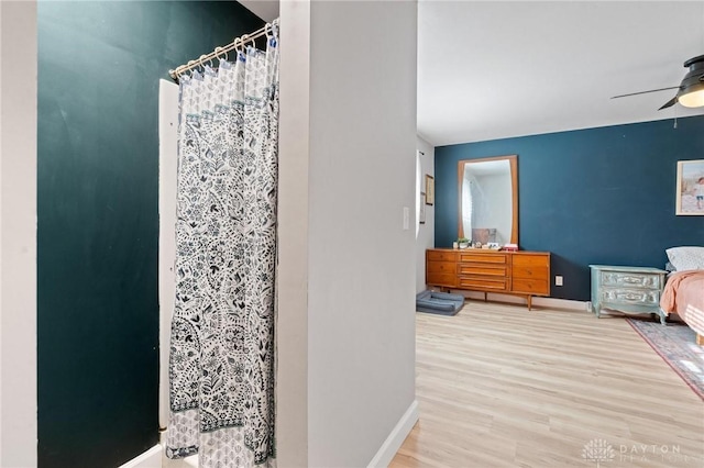 bathroom featuring hardwood / wood-style floors, curtained shower, and ceiling fan