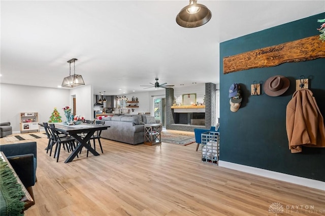 dining space with ceiling fan, a fireplace, and light wood-type flooring