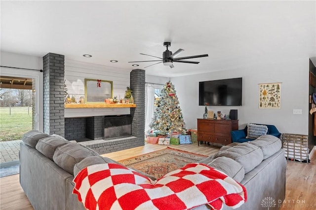 living room featuring ceiling fan, a fireplace, and light hardwood / wood-style flooring