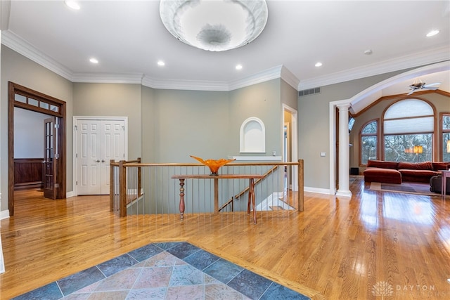 entryway with ceiling fan, ornate columns, crown molding, and light hardwood / wood-style flooring