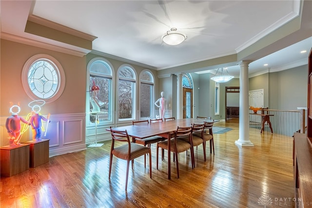 dining room with wood-type flooring, decorative columns, plenty of natural light, and ornamental molding