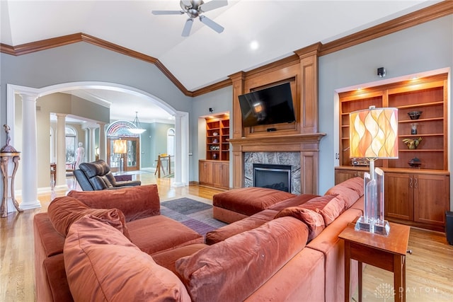 living room featuring a high end fireplace, ornamental molding, built in shelves, vaulted ceiling, and light hardwood / wood-style flooring