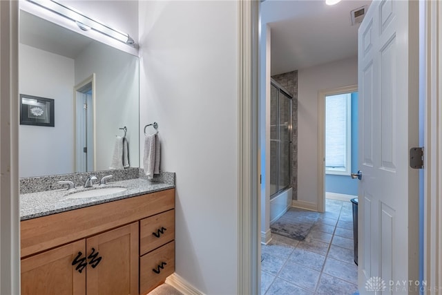 bathroom featuring tile patterned flooring, vanity, and bath / shower combo with glass door