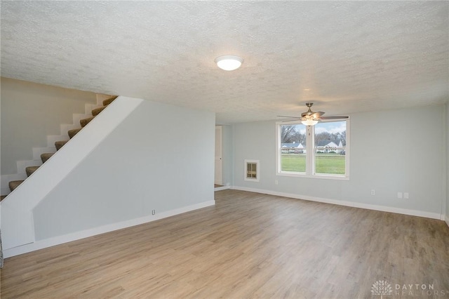 unfurnished living room featuring heating unit, ceiling fan, light hardwood / wood-style floors, and a textured ceiling