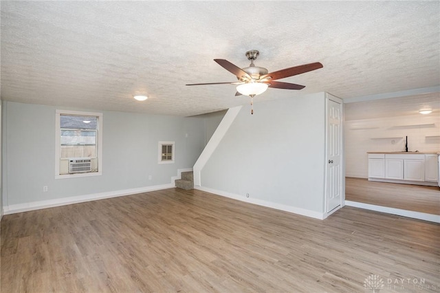 unfurnished living room with ceiling fan, light hardwood / wood-style flooring, and a textured ceiling