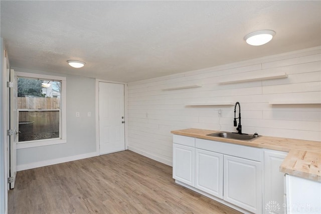 bar with white cabinetry, wooden counters, light hardwood / wood-style floors, and sink