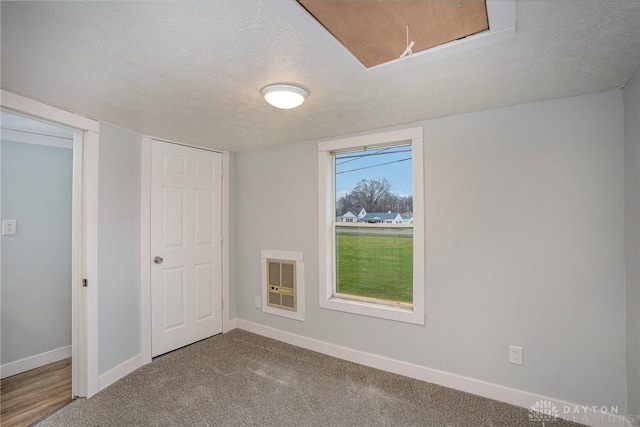 interior space with carpet, heating unit, and a textured ceiling