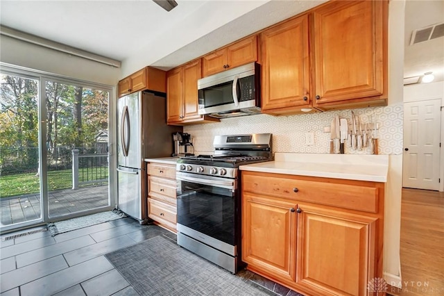 kitchen with backsplash, dark tile patterned flooring, and appliances with stainless steel finishes