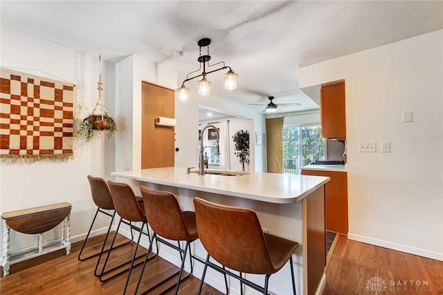 kitchen featuring a breakfast bar, sink, ceiling fan, decorative light fixtures, and kitchen peninsula