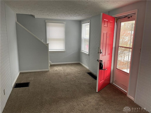 carpeted entryway featuring a textured ceiling