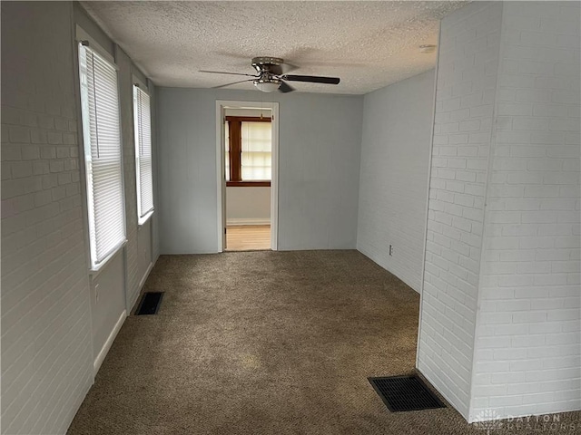 empty room with visible vents, carpet flooring, a textured ceiling, and ceiling fan