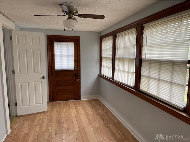 entryway featuring light wood finished floors, a textured ceiling, baseboards, and a ceiling fan