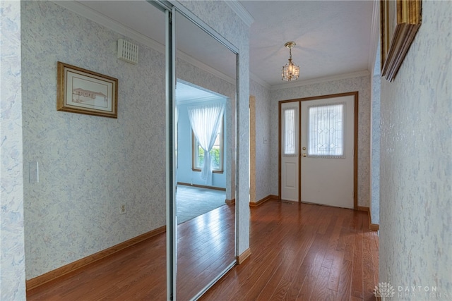 entrance foyer with crown molding, wood-type flooring, and an inviting chandelier