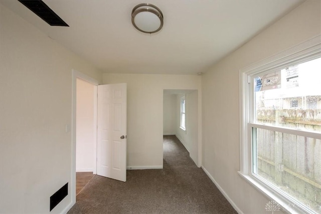 hallway featuring dark colored carpet