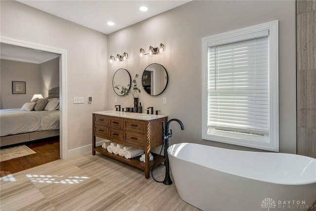 bathroom with wood-type flooring, vanity, a bathtub, and crown molding