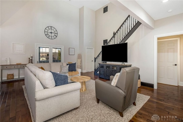 living room featuring dark hardwood / wood-style floors, a towering ceiling, and french doors