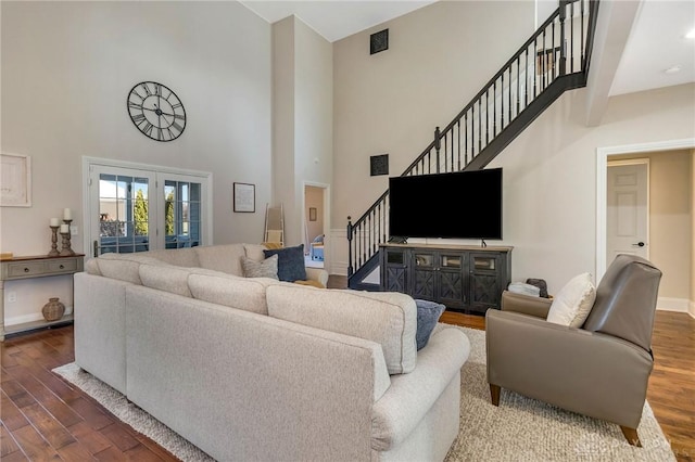 living room featuring french doors, a towering ceiling, and hardwood / wood-style flooring