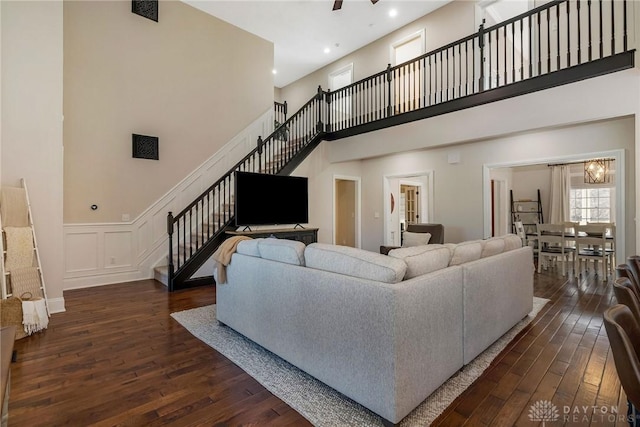 living room with dark hardwood / wood-style flooring, a towering ceiling, and ceiling fan