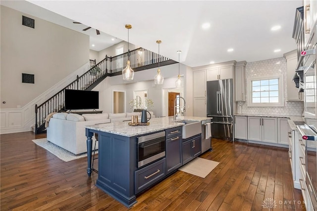 kitchen with white cabinetry, stainless steel appliances, a kitchen breakfast bar, decorative light fixtures, and a kitchen island with sink