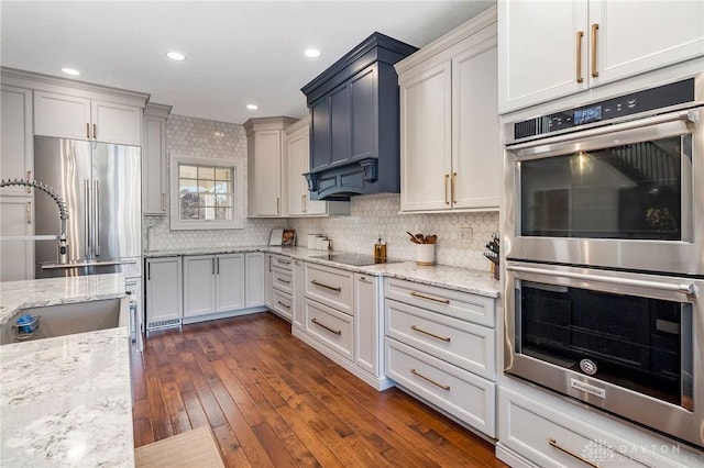 kitchen with appliances with stainless steel finishes, dark hardwood / wood-style floors, light stone counters, and tasteful backsplash