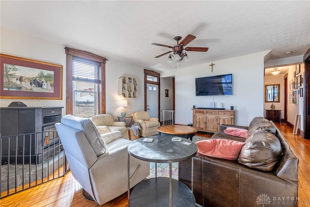 living room featuring ceiling fan, light hardwood / wood-style flooring, and a textured ceiling