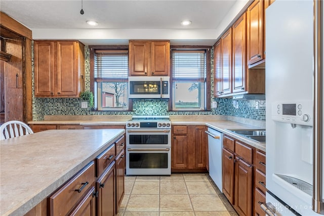 kitchen featuring sink, light tile patterned floors, a healthy amount of sunlight, and appliances with stainless steel finishes