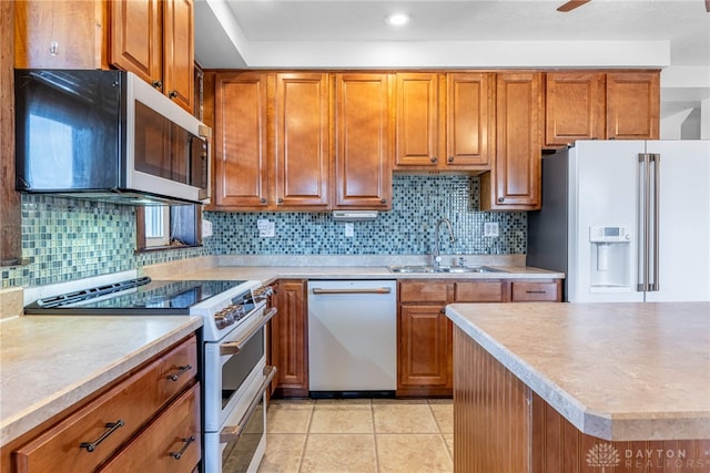 kitchen with high end appliances, light tile patterned floors, sink, and tasteful backsplash