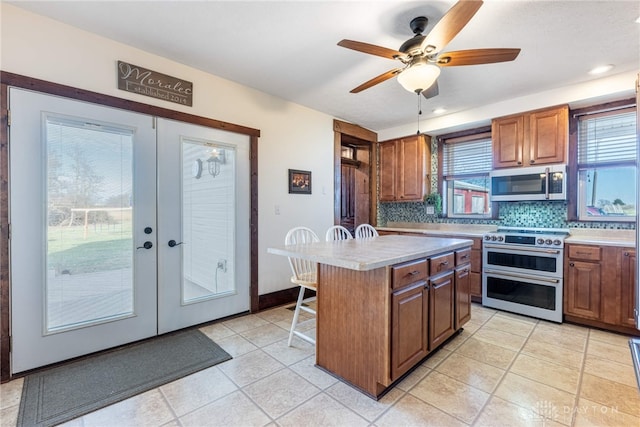 kitchen with a center island, french doors, stainless steel appliances, tasteful backsplash, and a breakfast bar area