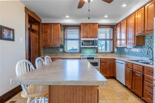 kitchen with a kitchen bar, stainless steel range, white dishwasher, sink, and a center island