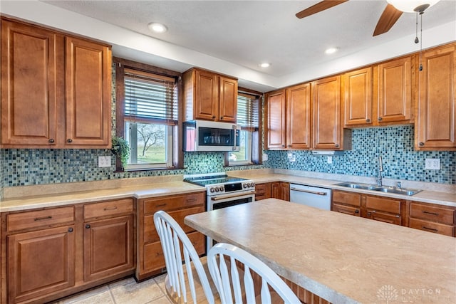 kitchen with appliances with stainless steel finishes, tasteful backsplash, light tile patterned floors, and sink