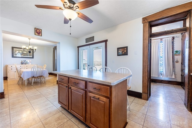 kitchen with a center island, pendant lighting, a textured ceiling, light tile patterned floors, and ceiling fan with notable chandelier