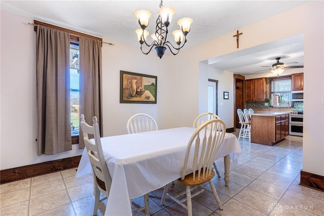 tiled dining room featuring ceiling fan with notable chandelier