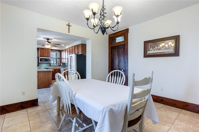 tiled dining space featuring ceiling fan with notable chandelier