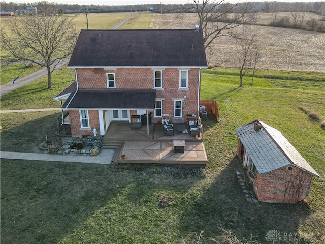 rear view of property with a lawn, an outdoor living space, an outbuilding, a wooden deck, and a rural view