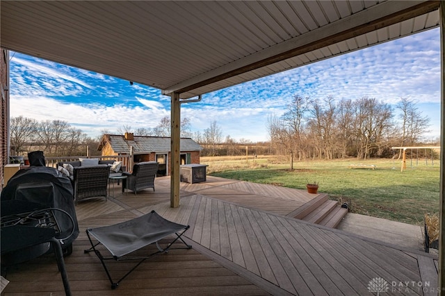 wooden terrace with an outdoor living space, an outbuilding, and a yard