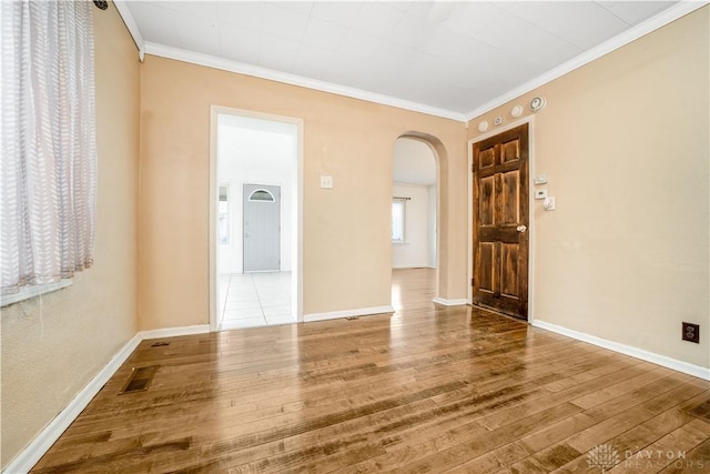 empty room with hardwood / wood-style floors and crown molding