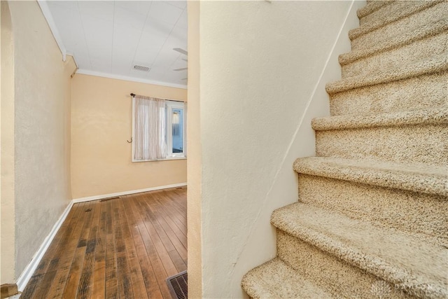 staircase with hardwood / wood-style floors and ornamental molding