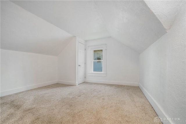 additional living space featuring carpet and vaulted ceiling