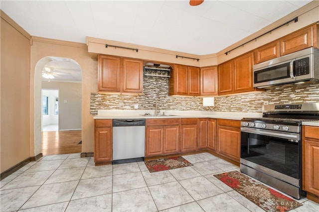 kitchen with ceiling fan, sink, stainless steel appliances, backsplash, and crown molding