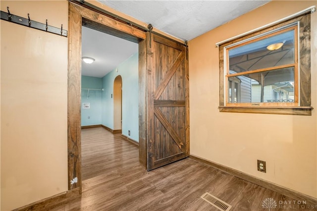 corridor with hardwood / wood-style floors and a barn door