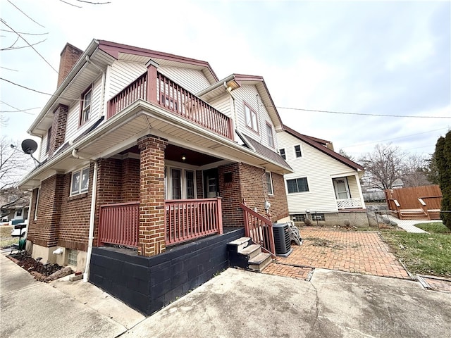 view of home's exterior with a porch, a balcony, and central AC